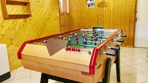 Una mesa de futbolín en una habitación con paredes de madera y suelo de baldosas.