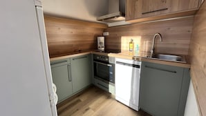 Una cocina compacta equipada con horno, lavavajillas y cafetera.