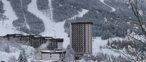 A snow-covered mountain landscape with a ski resort, including buildings and ski lifts.