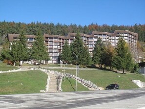 A multi-story building with balconies, surrounded by trees and a grassy area. - 5th floor, view ski slopes, balcony, parking, tv, 43m², Villard de Lans (Villard-de-Lans)