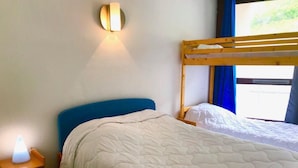 Une chambre avec deux lits, une table de chevet avec une lampe et un luminaire fixé au mur.