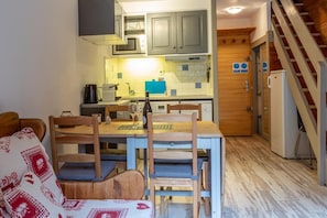 Kompakti keittiö, jossa on ruokailutila, puukaapit ja portaat.