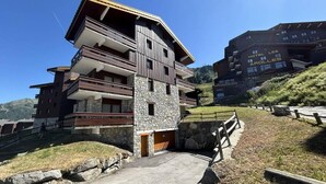 Ein mehrstöckiges Hotel mit Balkonen und einer Steinaußenfassade, gelegen in einer hügeligen Gegend.
