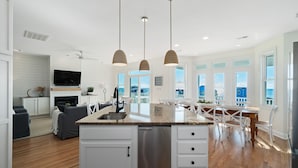 A spacious kitchen with a central island, white cabinetry, and a stainless steel dishwasher. - 'Coastal Vista' - Walk to Emerald Isle Beach! (Emerald Isle)