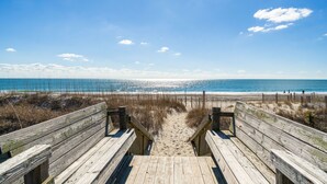 A wooden boardwalk leading to a beach with a clear view of the ocean and a sandy path. - 'Coastal Vista' - Walk to Emerald Isle Beach! (Emerald Isle)