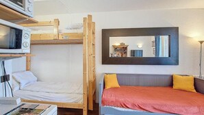 Habitación pequeña con literas, un escritorio con computadora y un espejo en la pared.