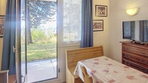 Un dormitorio con una cama de madera, un escritorio con una mesa, un aparador y una ventana con cortinas.