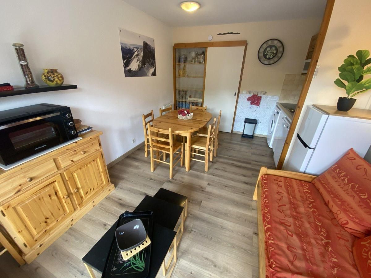 A compact living space with a dining table, chairs, a sofa, a kitchen area, and a microwave.