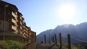 Un bâtiment en bois doté de nombreux balcons, un chemin pavé et un paysage montagneux en arrière-plan.