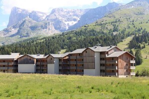 Una hilera de edificios de estilo chalet de madera con balcones, con montañas al fondo.