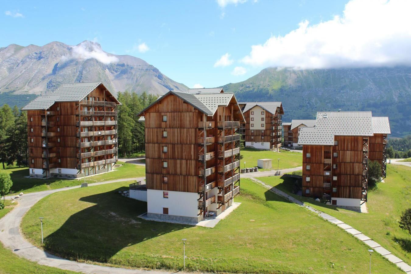 A cluster of wooden buildings with balconies, set against a mountainous backdrop.