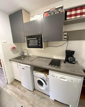 A compact kitchenette with a microwave, coffee maker, and a washing machine. - Ski-in/ski-out & foot of the slopes, 7th floor, view ski slopes, balcony, parking, tv, 28m² (Le Dévoluy)