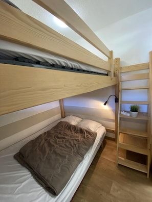 A bunk bed with a lower bunk, a bedside table with a lamp, and a shelf unit with a plant. - Ski-in/ski-out & foot of the slopes, 7th floor, view ski slopes, balcony, parking, tv, 28m² (Le Dévoluy)