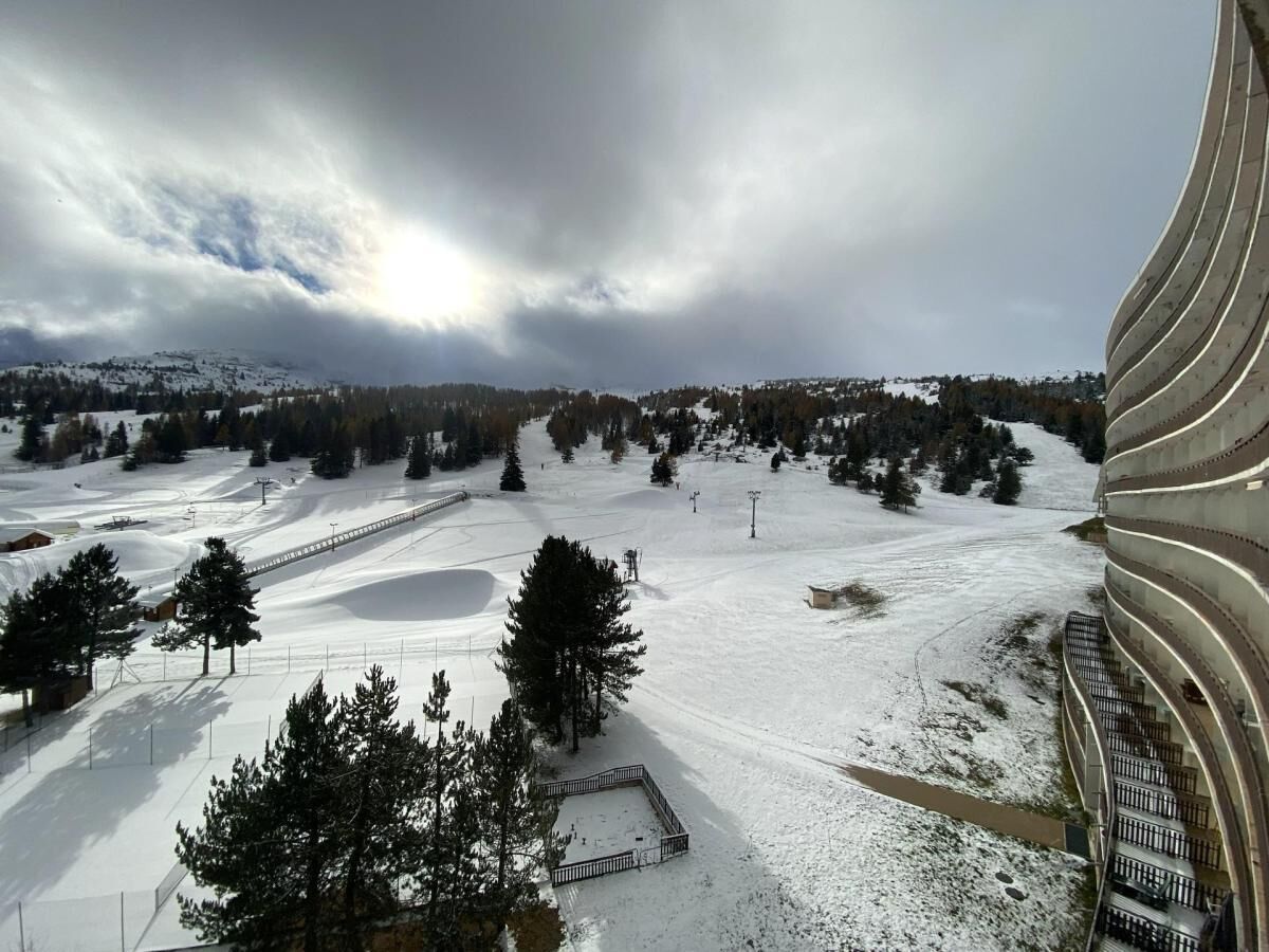 A snow-covered ski slope with a modern building with curved architecture.