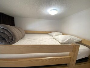Ein Etagenbett mit Kopfstütze, einem Kissen und einer Decke.