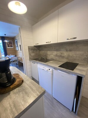 A modern kitchen with white cabinets, a built-in dishwasher, and a countertop with a coffee maker. - Ski-in/ski-out & foot of the slopes, 12nd floor, view mountain, balcony, parking, tv, 28m² (Le Dévoluy)