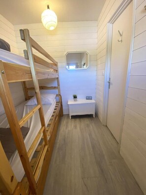 A small, narrow room with a bunk bed, a small white bench, a mirror, and a door. - Ski-in/ski-out & foot of the slopes, 12nd floor, view mountain, balcony, parking, tv, 28m² (Le Dévoluy)