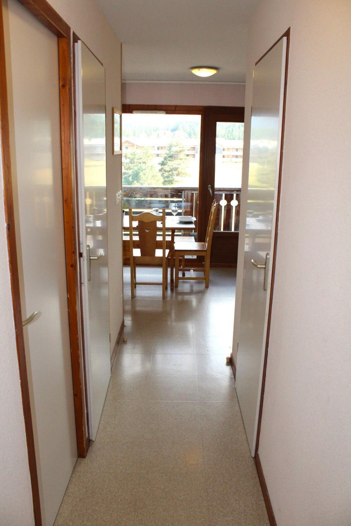 Un couloir étroit, avec des portes en bois donnant sur un balcon.