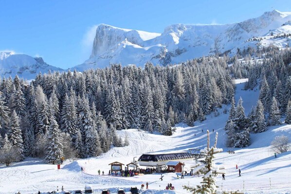A snow-covered ski resort with a lodge, ski slopes, and a mountain backdrop. - 200m from resort center, 6th floor, view mountain, balcony, tv, 23m², Superdévoluy (Le Dévoluy)