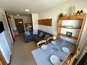 A compact living space with a kitchenette, a dining area, and a seating area with a sofa and chairs.