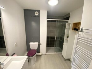Ein kleines Badezimmer mit Toilette, Dusche und einem weißen Schrank.