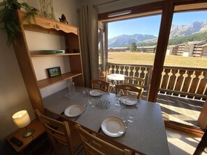 Ein Essbereich mit einem Tisch für vier Personen, Stühlen, einer Lampe und Bergblick durch ein Fenster.