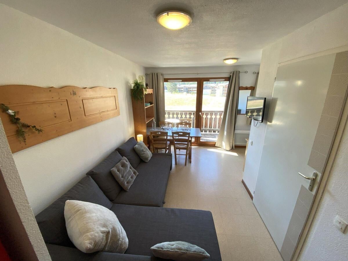 Ein Zimmer mit einer Couch, einem Esstisch, Stühlen und einem Fernseher.