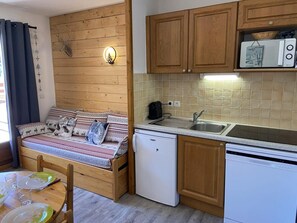 A compact kitchen with wooden cabinets, a small refrigerator, a microwave, and a sink. - 100m from ski lifts, Ground floor, terrace, tv, 28m², La Joue du Loup (Le Dévoluy)