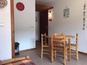 A room with a wooden dining table and chairs, a red clock, and a small black appliance. - 100m from resort center, Ground floor, terrace, tv, 28m², La Joue du Loup (Le Dévoluy)