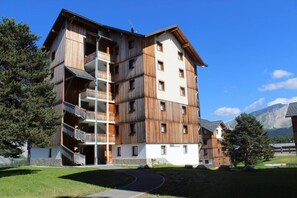Un edificio de madera de varios pisos con balcones, con montañas al fondo.