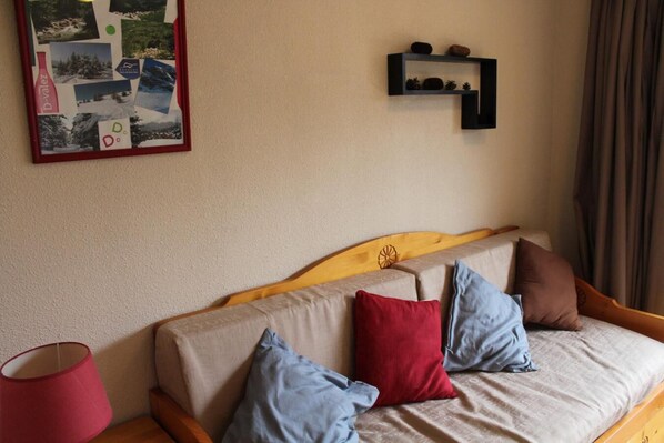 Una cama con cabecera de madera, una lámpara roja y un estante con adornos.