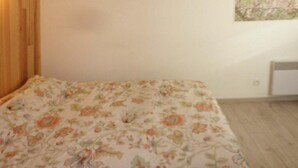 A bedroom with a floral bedspread, a wooden wardrobe, and a wall-mounted map.