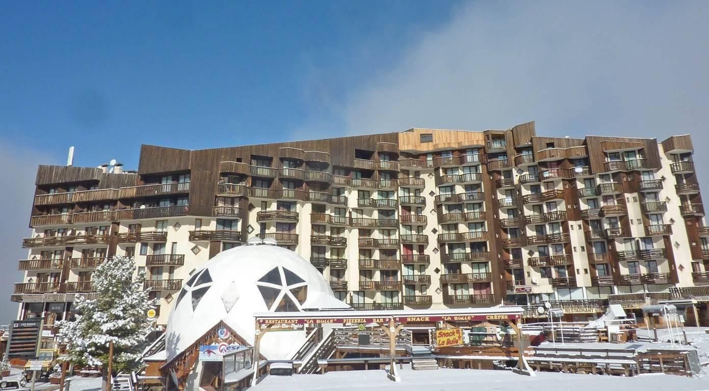 A multi-story hotel with balconies and a large white dome structure in the foreground.