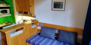 A compact room with a wooden bench, a microwave, a small stove, and a framed picture on the wall. - 300m from ski slopes, 5th floor, balcony, tv, 33m², Les Arcs (Les Arcs)