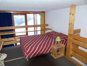 A small, single-bed room with a wooden bunk bed structure, a bedside table with a lamp, and a window with curtains. - 300m from ski slopes, 5th floor, balcony, tv, 33m², Les Arcs (Les Arcs)