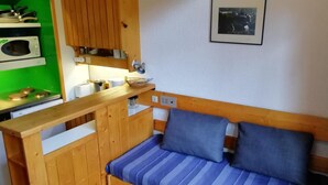 A compact room with a wooden bench, a microwave, a small stove, and a framed picture on the wall. - 300m from ski slopes, 5th floor, balcony, tv, 33m², Les Arcs (Les Arcs)