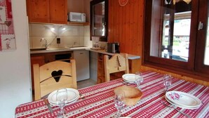Una cocina acogedora con armarios de madera, un microondas y un comedor con mesa dispuesta para cuatro.