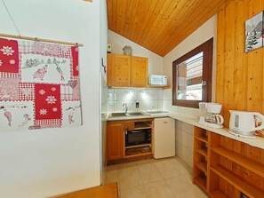 A compact kitchen with wooden cabinets, a microwave, a coffee maker, and a small oven. - 3rd floor, view mountain, balcony, tv, ski locker, 27m², Le Grand Bornand (Le Grand-Bornand)