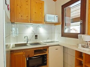 A compact kitchen with wooden cabinets, a microwave, a built-in oven, and a coffee maker.