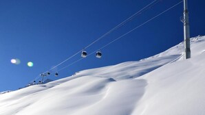 A ski lift with cabins moving up a snowy slope. - 10m from ski slopes, balcony, ski locker, 16m², Méribel-Mottaret (Méribel - Les Allues)
