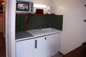 A compact kitchenette with a built-in microwave, a coffee maker, and a sink.