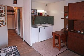 A compact kitchen with a microwave, sink, and wooden cabinets.