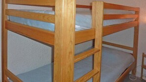 A bunk bed with a wooden frame and blue bedding. - Resort center, balcony, tv, 25m², Les Orres (Les Orres)