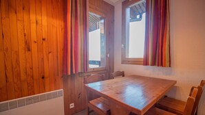 A wooden-paneled room with a wooden table and chairs, a window with curtains, and a radiator. - 200m from ski slopes, 1st floor, balcony, ski locker, 31m², Valmorel (Valmorel)