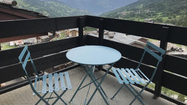 A balcony with a round table and two chairs, overlooking a mountainous landscape. - 200m from ski slopes, 1st floor, balcony, ski locker, 31m², Valmorel (Valmorel)