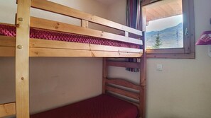 Un lit superposé avec une fenêtre, un tapis rouge et une vue sur une montagne.