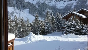 A mountain cabin with a view of a snowy landscape and a ski lift.