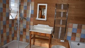 A bathroom with a shower, a sink, a mirror, and a towel rack.