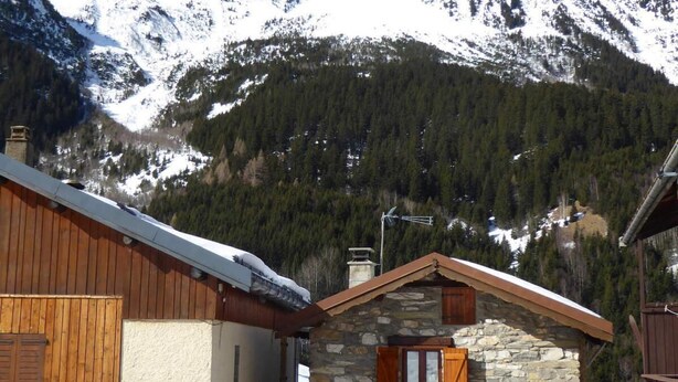 A stone building with wooden shutters and a wooden roof, surrounded by snow-covered mountains and a forested area. - Chalet, terrace, tv, ski locker, 60m², Pralognan-la-Vanoise (Pralognan-la-Vanoise)