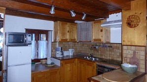 A kitchen with wooden cabinets, a microwave, a refrigerator, a sink, and a stove. - Chalet, terrace, tv, ski locker, 60m², Pralognan-la-Vanoise (Pralognan-la-Vanoise)